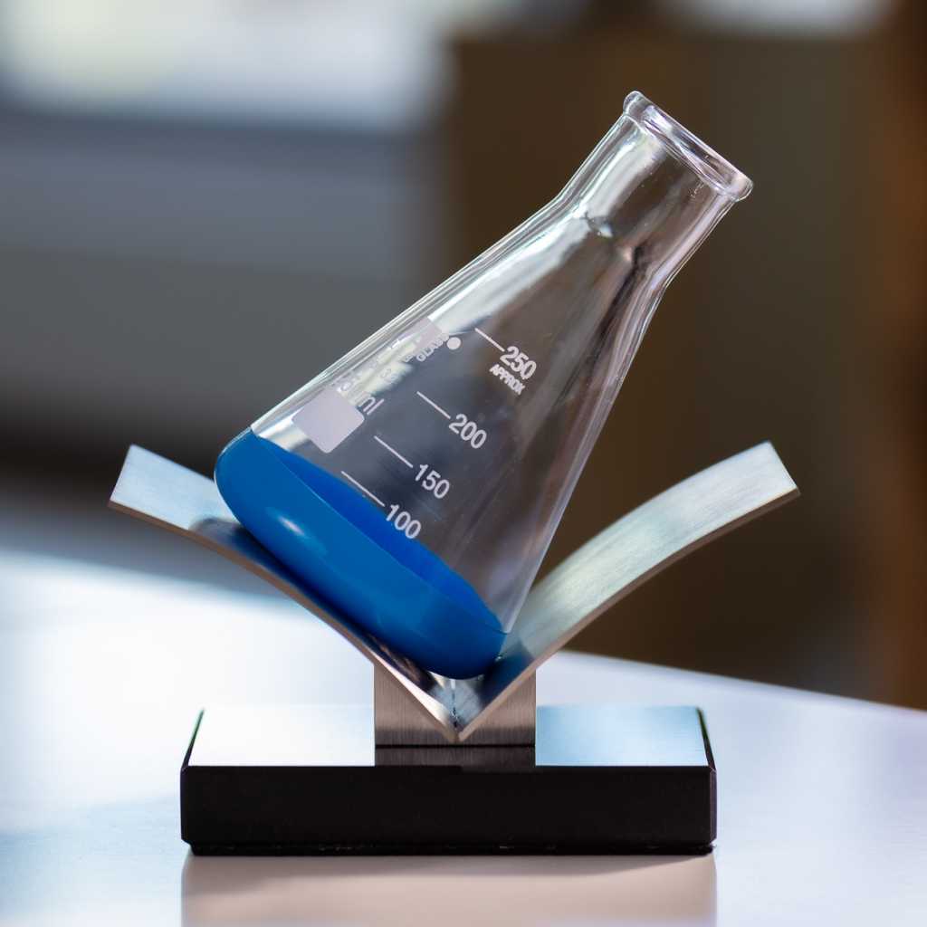 Metal pedestal with stone base. Glass bottle sandblasted, painted and baked.